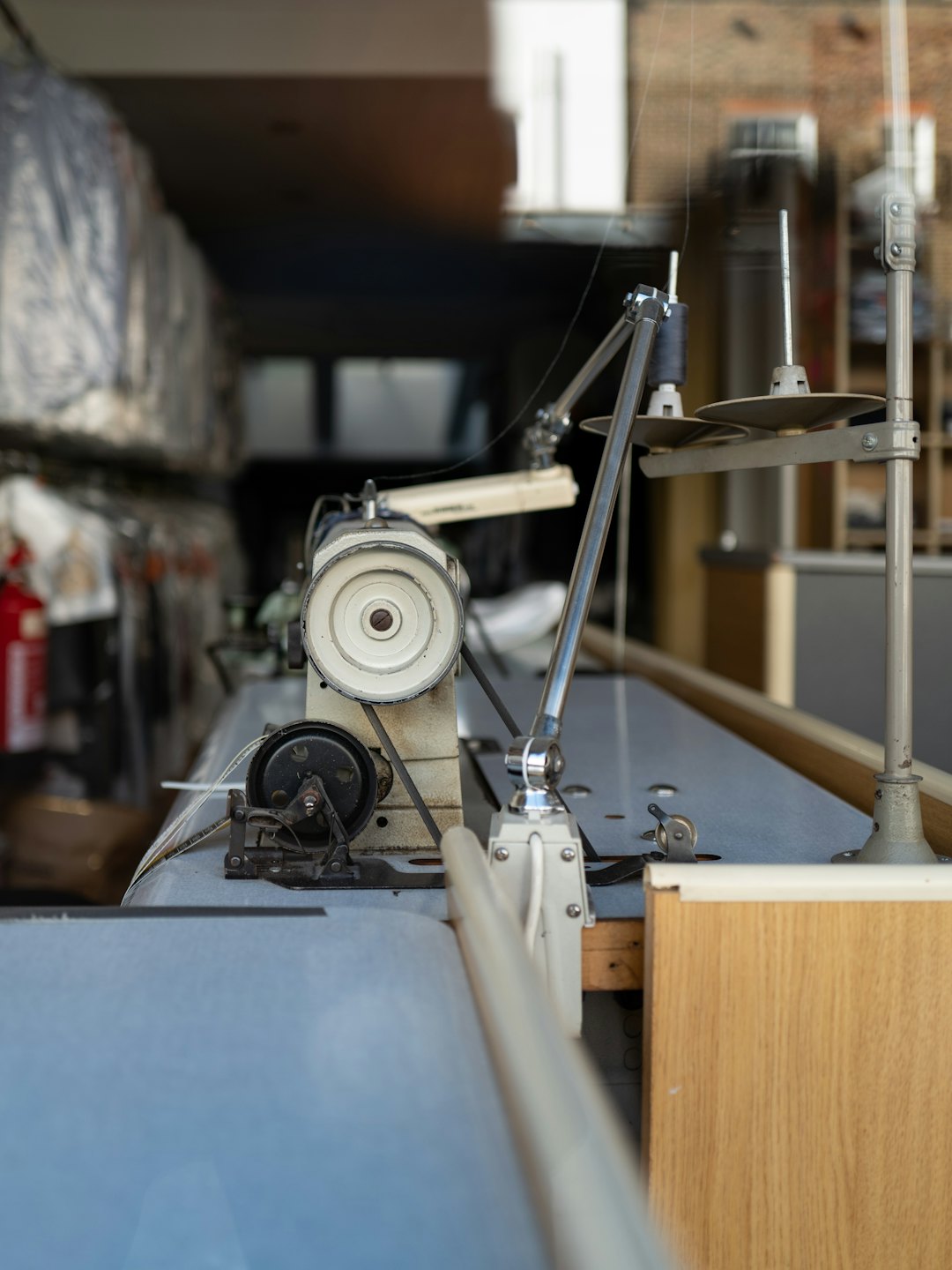 Máquina de coser industrial sobre un banco de trabajo azul grisáceo claro.